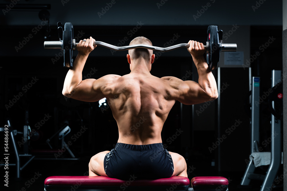 Man in gym or fitness studio on weight bench Man in gym or fitness studio on weight bench