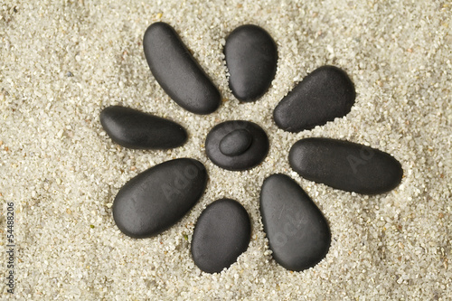 Canvas Print Flower with black stones on the sand