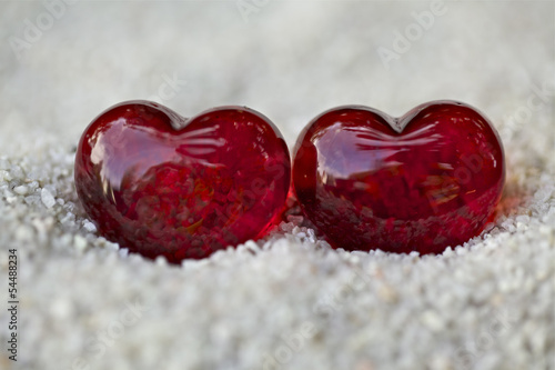 Canvas Print Symbol of love, two red hearts with stones on the sand.