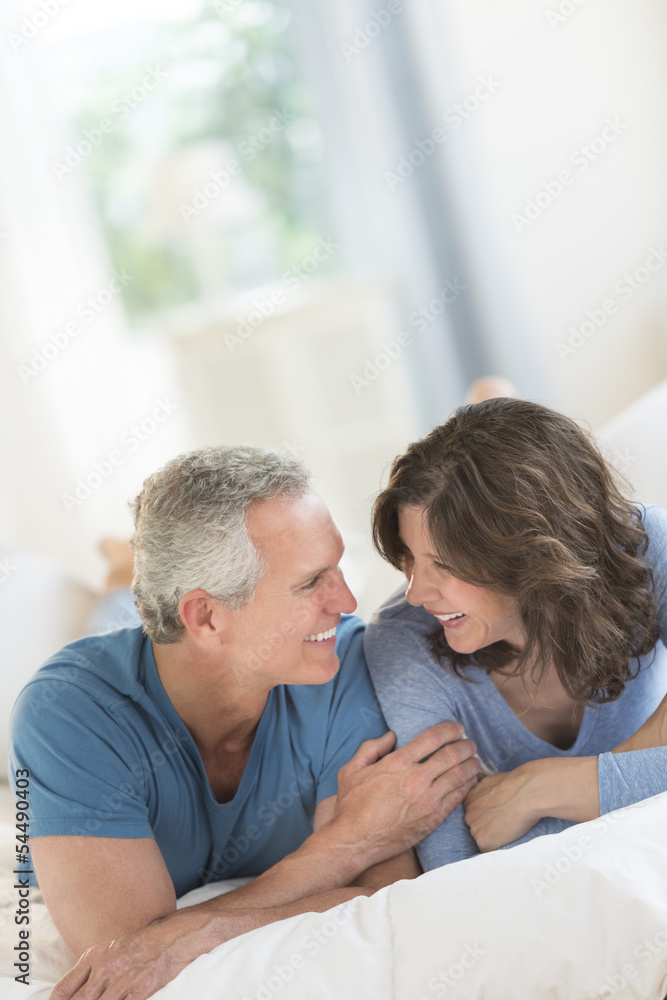 Couple Looking At Each Other While Relaxing In Bed Couple Looking At Each Other While Relaxing In Bed