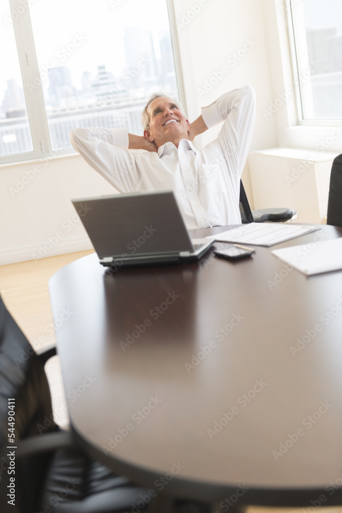 Happy Businessman With Hands Behind Head Sitting At Desk Happy Businessman With Hands Behind Head Sitting At Desk