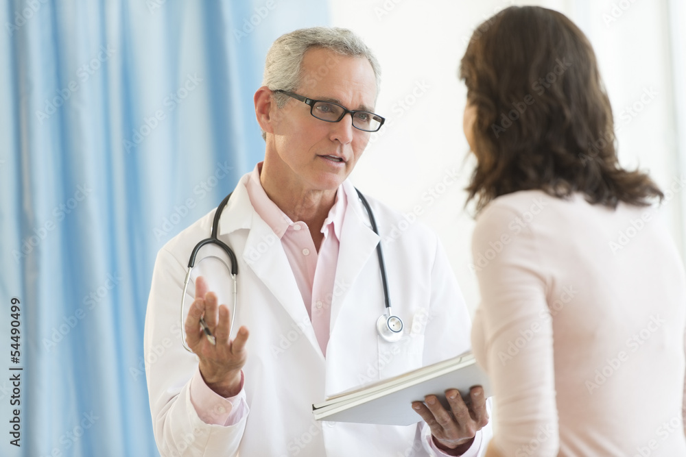 Male Doctor Discussing With Patient In Clinic Male Doctor Discussing With Patient In Clinic