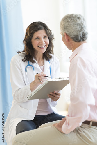 Happy Doctor With Clipboard Looking At Patient