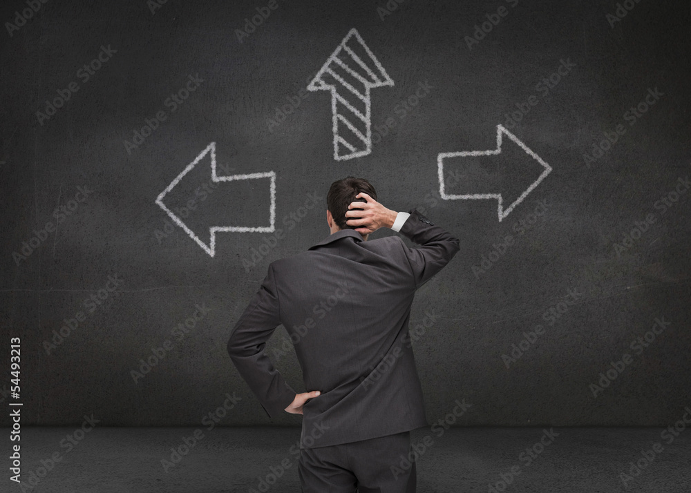 Thoughtful businessman looking at three arrows Thoughtful businessman looking at three arrows