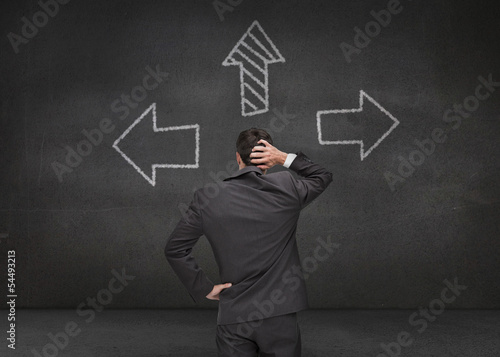 Canvas Print Thoughtful businessman looking at three arrows
