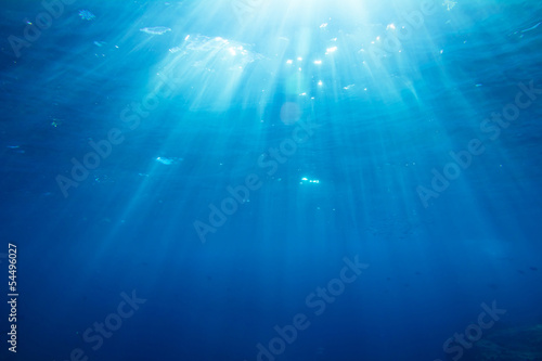 Underwater shot with sunrays and fishes in deep tropical sea