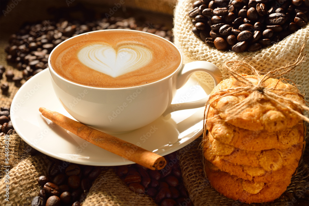 Fototapeta premium Filiżanka cafe latte z ziaren kawy i ciasteczek