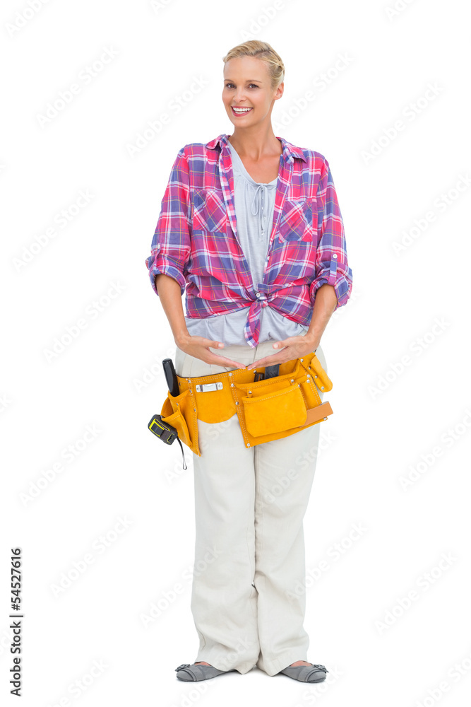 Smiling blonde wearing a tool belt in ballerina pose Smiling blonde wearing a tool belt in ballerina pose