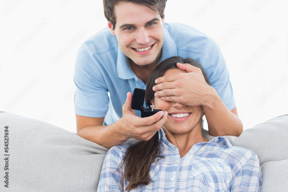 Man hiding his girlfriends eyes and offering her an engagement r Man hiding his girlfriends eyes and offering her an engagement r
