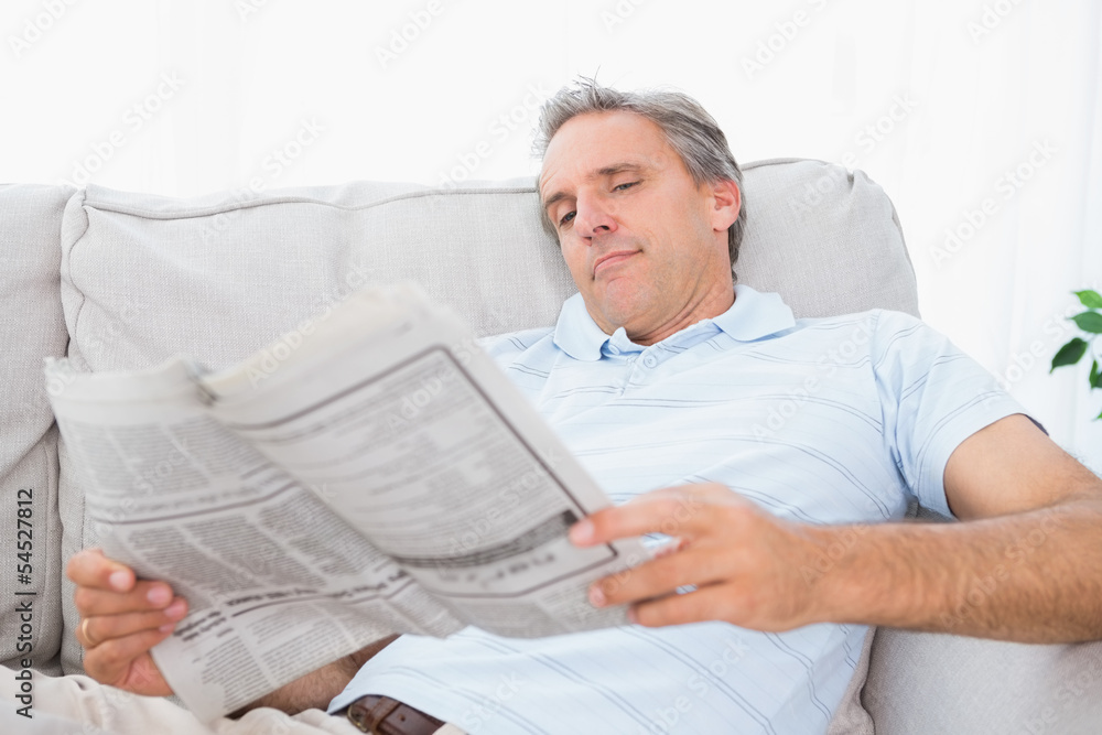 Obraz premium Man reading the newspaper on couch