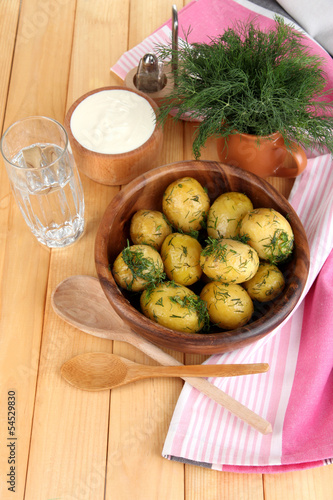Boiled potatoes on wooden bowl near napkin on wooden table