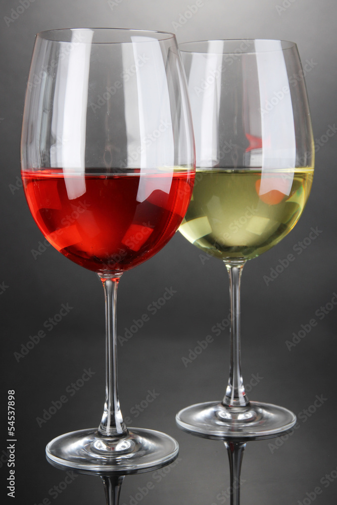 Red and white wine in glasses on grey background Red and white wine in glasses on grey background