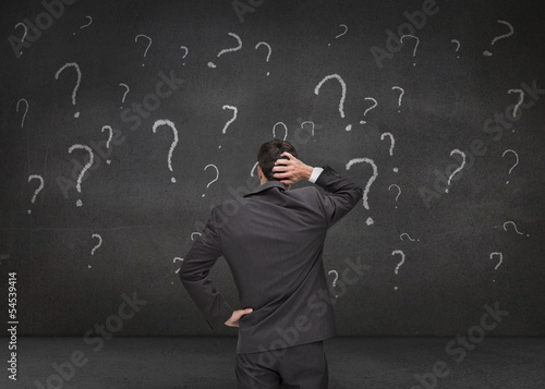 Foto Rear view of a doubtful businessman looking at various question