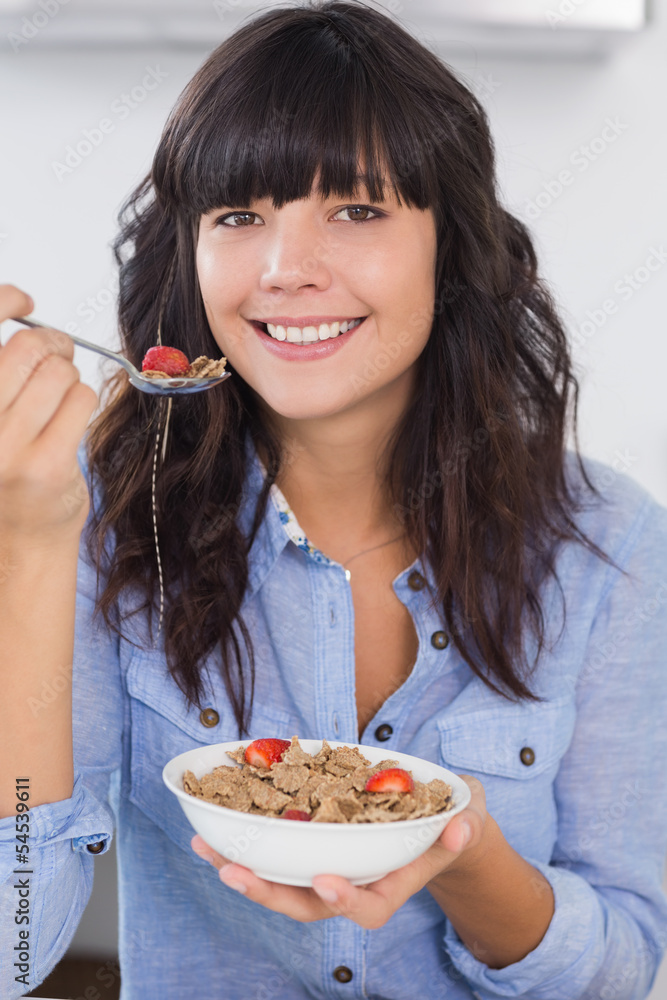 Pretty brunette having bowl of cereal and fruit