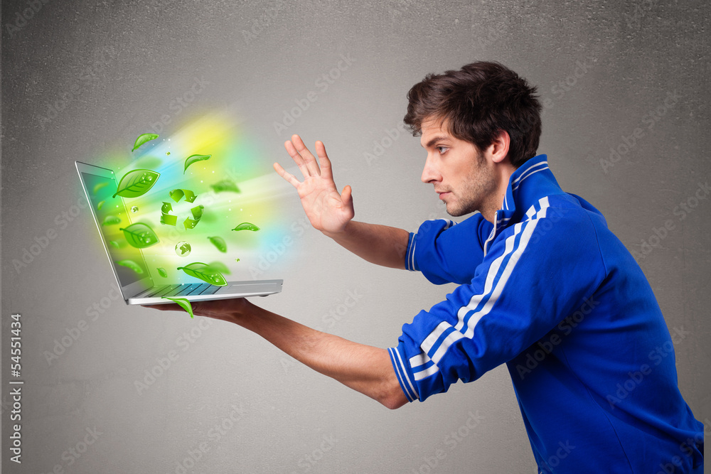 Casual boy holding laptop with recycle and environmental symbols Casual boy holding laptop with recycle and environmental symbols
