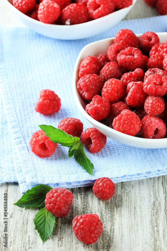Ripe sweet raspberries in bowls on wooden background Ripe sweet raspberries in bowls on wooden background