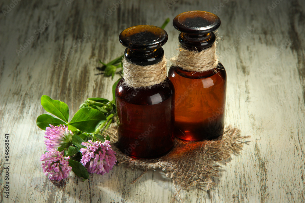 Medicine bottles with clover flowers on wooden table Medicine bottles with clover flowers on wooden table