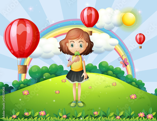 A girl eating an ice cream at the hilltop with hot air balloons