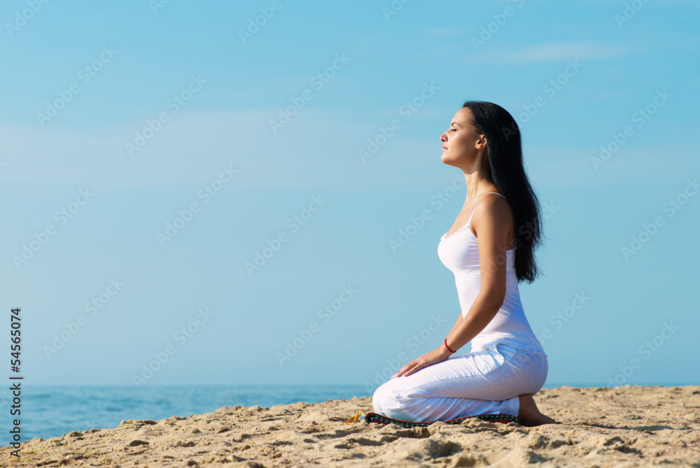 Woman in white clothes meditating on beach, portrait in profile Woman in white clothes meditating on beach, portrait in profile