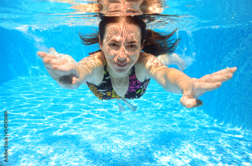 Happy smiling woman swims underwater in pool
