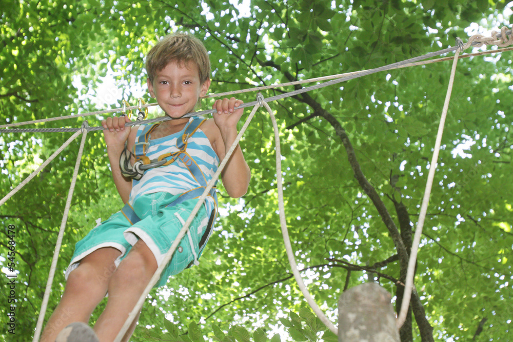 young happy child boy in adventure park in safety equipment