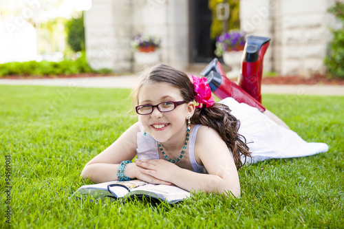 Preteen young girl laying in grass reading and smiling © Mary Perry