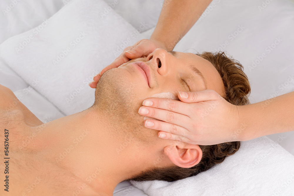 Facial massage. Top view of relaxed young men lying on the massa