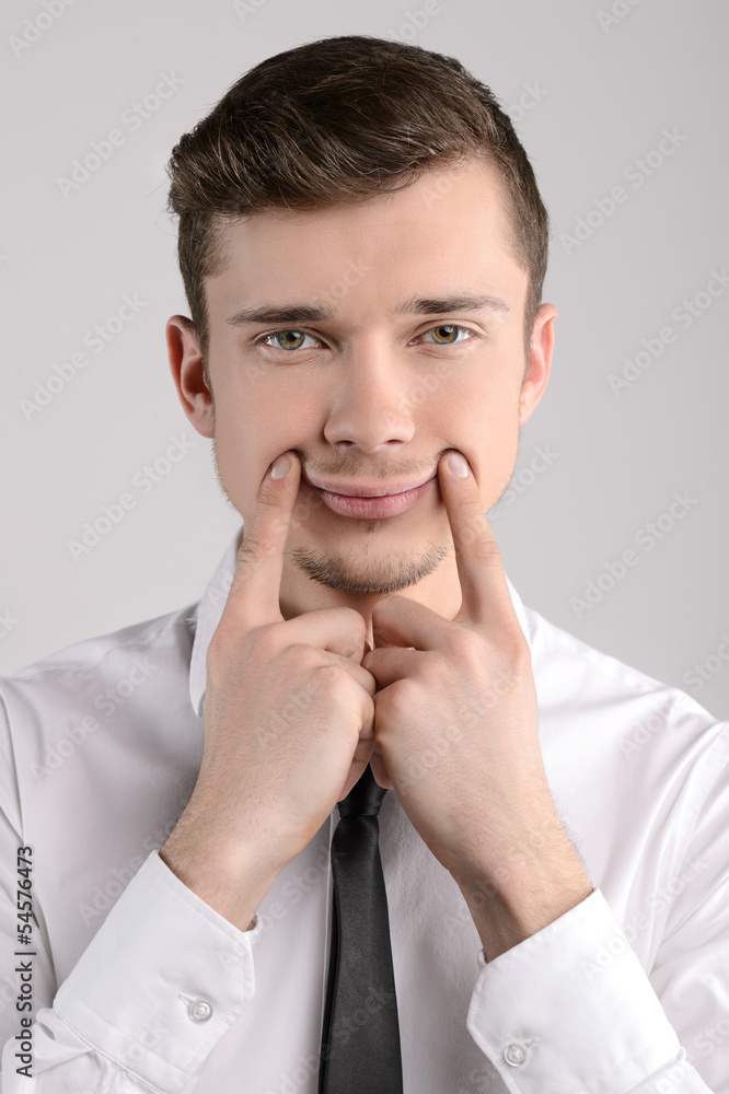 Making a face. Portrait of businessman making a forced smile by Making a face. Portrait of businessman making a forced smile by