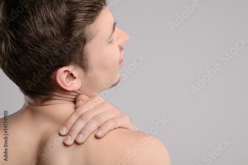 Pain in shoulder. Rear view of young shirtless men touching his