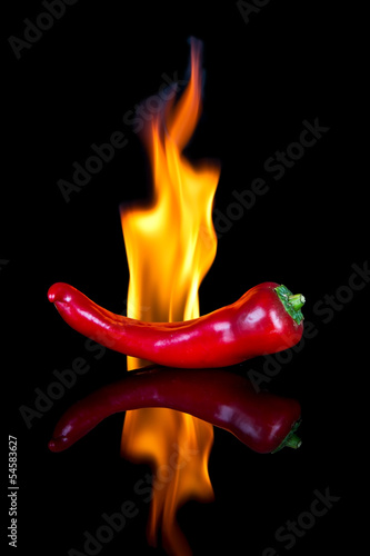 Red chilli on black surface with flames