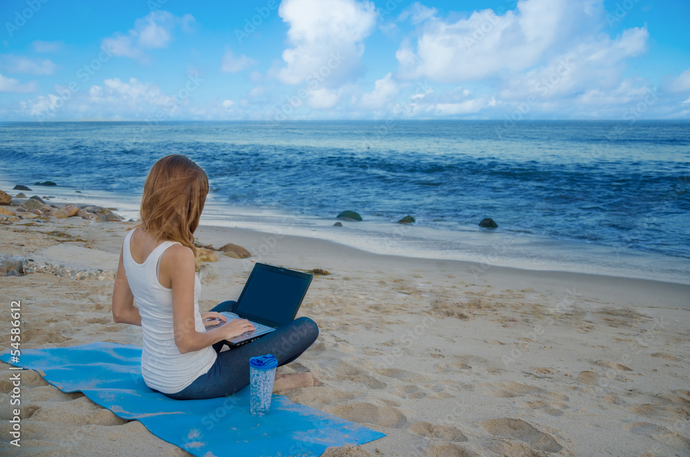 Yang woman with laptop by the ocean
