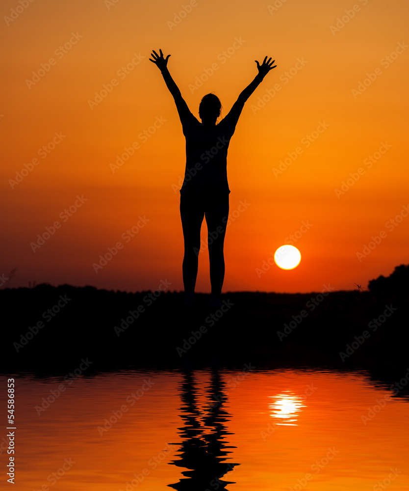 Silhouette woman jumping against orange sunset Silhouette woman jumping against orange sunset