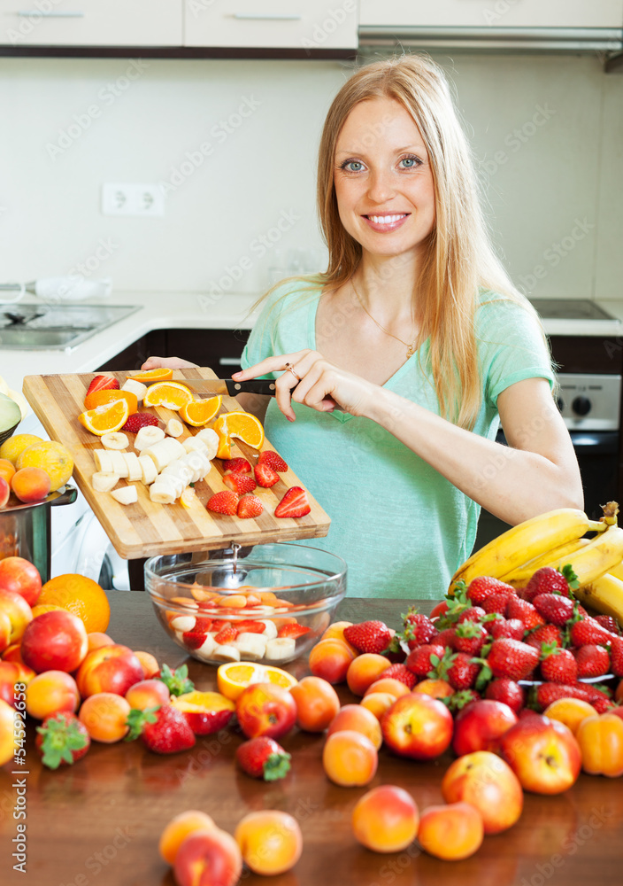 Happy  blonde woman cutting fruits