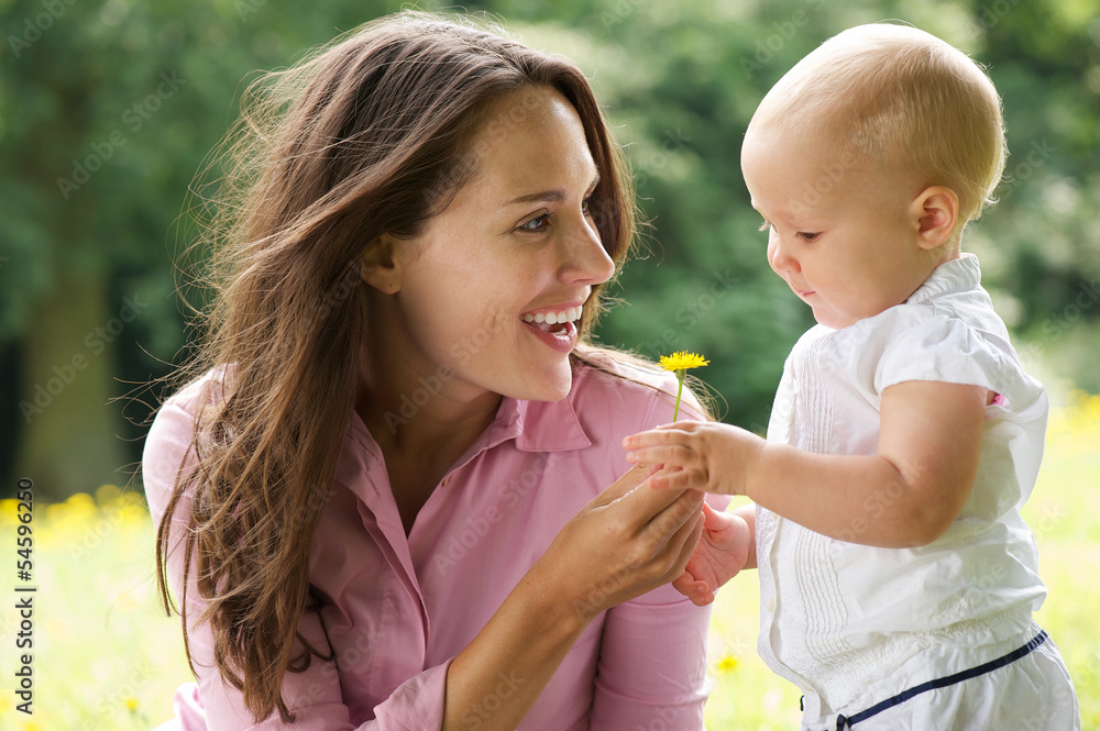 Happy mother giving flower to baby in the park Happy mother giving flower to baby in the park