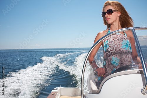 Fotografie, Obraz Woman  in Dress Driving A Speedboat Fast At Sea