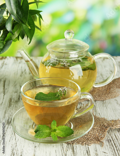 Teapot and cup of herbal tea with fresh mint flowers