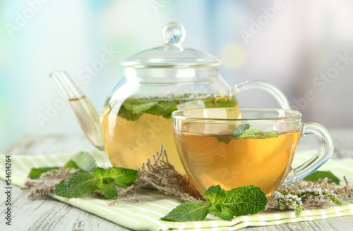 Teapot and cup of herbal tea with fresh mint flowers