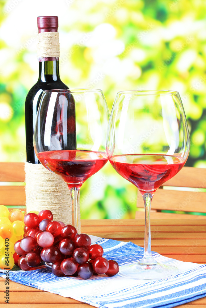 Glasses of wine on napkin on wooden table on nature background