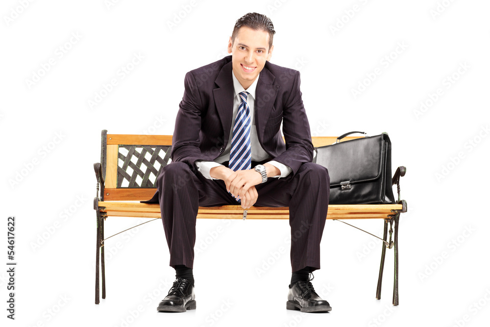 Smiling young businessman sitting on a wooden bench Smiling young businessman sitting on a wooden bench