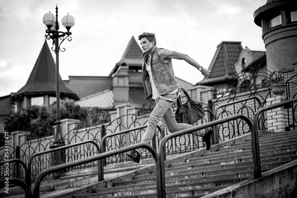 Fototapeta premium black-and-white photo of a guy with a bag of fashion, running up