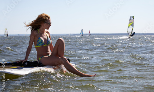 young beautiful woman on windsurfing in water
