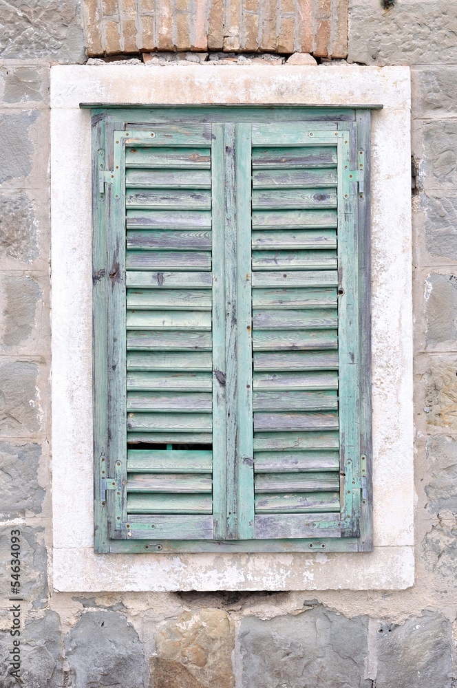 The old window with blue closed shutters on a old house The old window with blue closed shutters on a old house