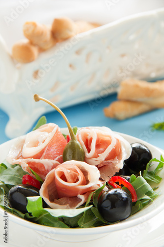 Salad with arugula, prosciutto and olives.