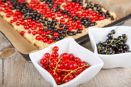 red and black currant berries with home baked cake on background