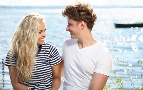 Young beautiful couple in love sitting near the water