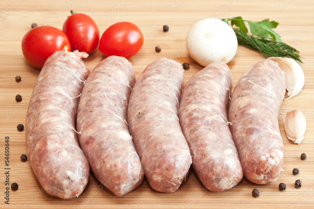 Uncooked sausages with vegetables on the chopping board Uncooked sausages with vegetables on the chopping board