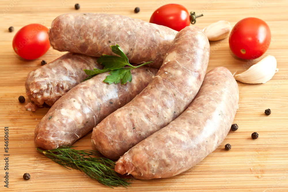 Uncooked sausages with vegetables on the chopping board Uncooked sausages with vegetables on the chopping board