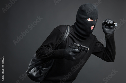 Thief. Side view of men in black balaclava holding a gun and fla