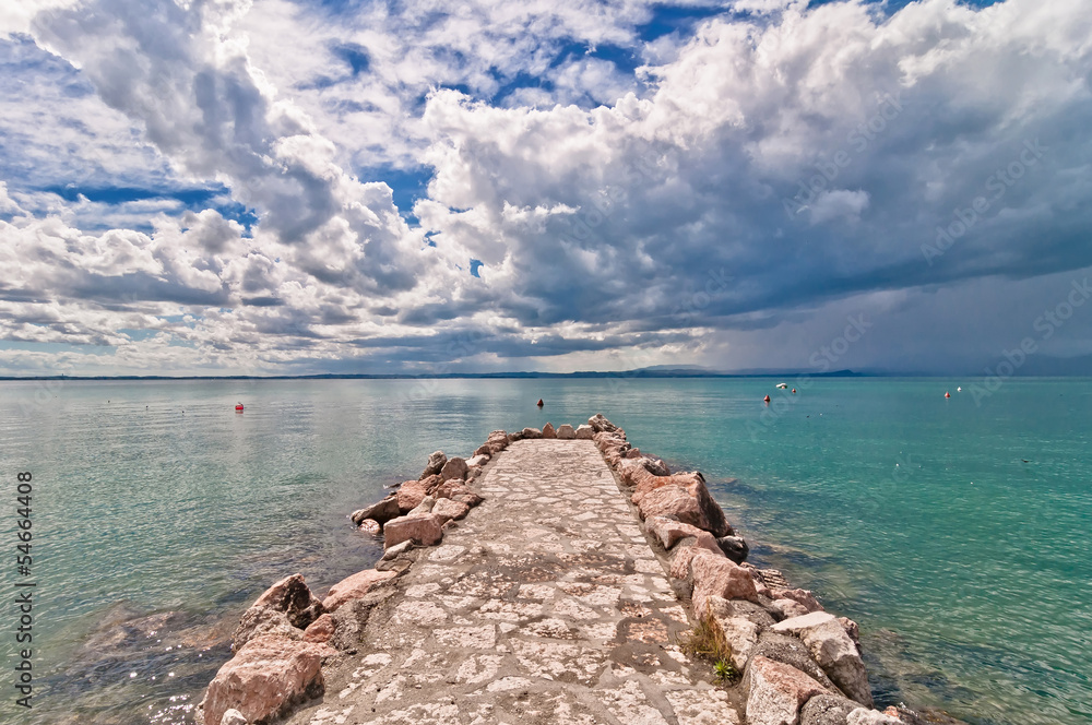 pier and cloudy dramatic sky over Garda lake - Italy