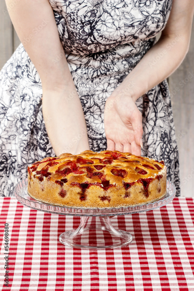 Woman holding cake stand with strawberry cake. Birthday party